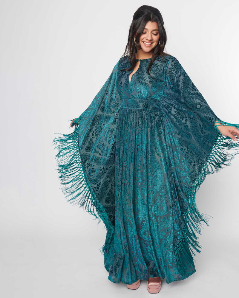 Front of a model wearing a size 5X Unique Vintage Emerald Floral Fringe Flutter Sleeve Caftan in Green Floral by Unique Vintage. | dia_product_style_image_id:316966